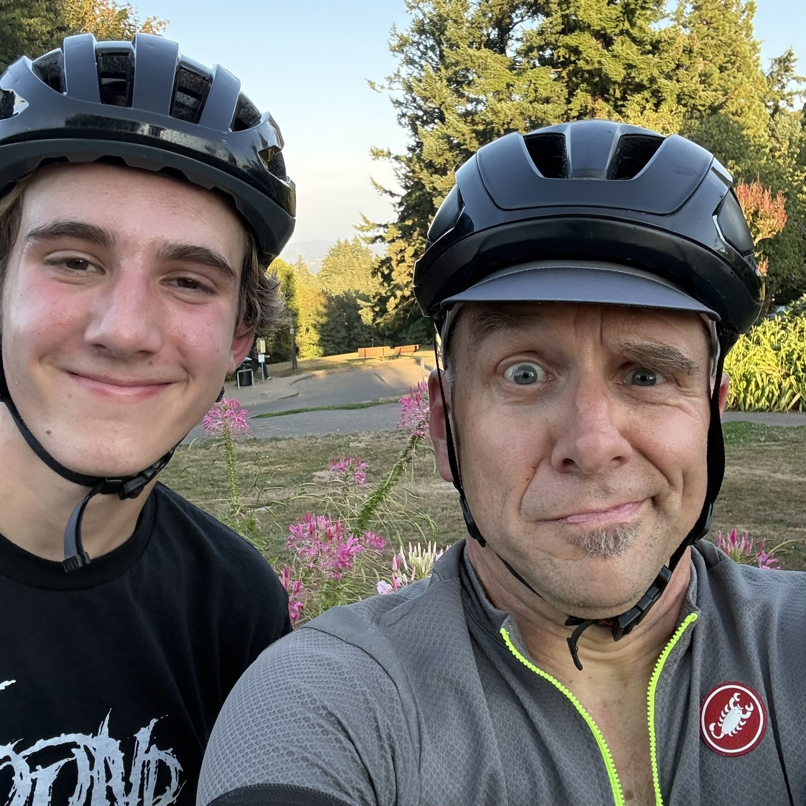 Father and son wearing quizzical expressions and bicycle helmets, Mt. Hood in the hazy background