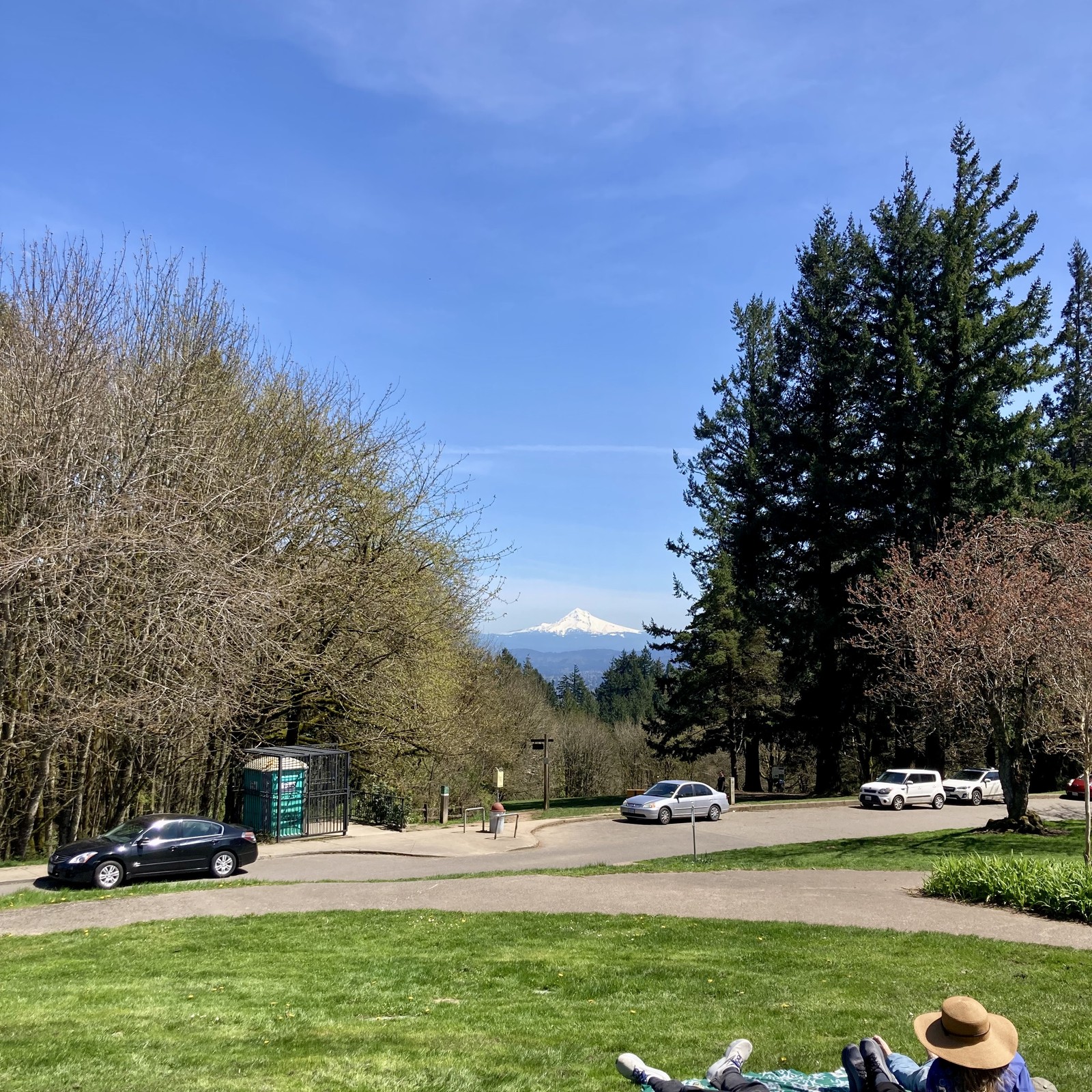 View toward Mt. Hood from Council Crest Park. Air is crystal clear, about 68°F. Mountain brilliant with a coat of snow. In the very near foreground, less than 15' away, are two people lying on the grass