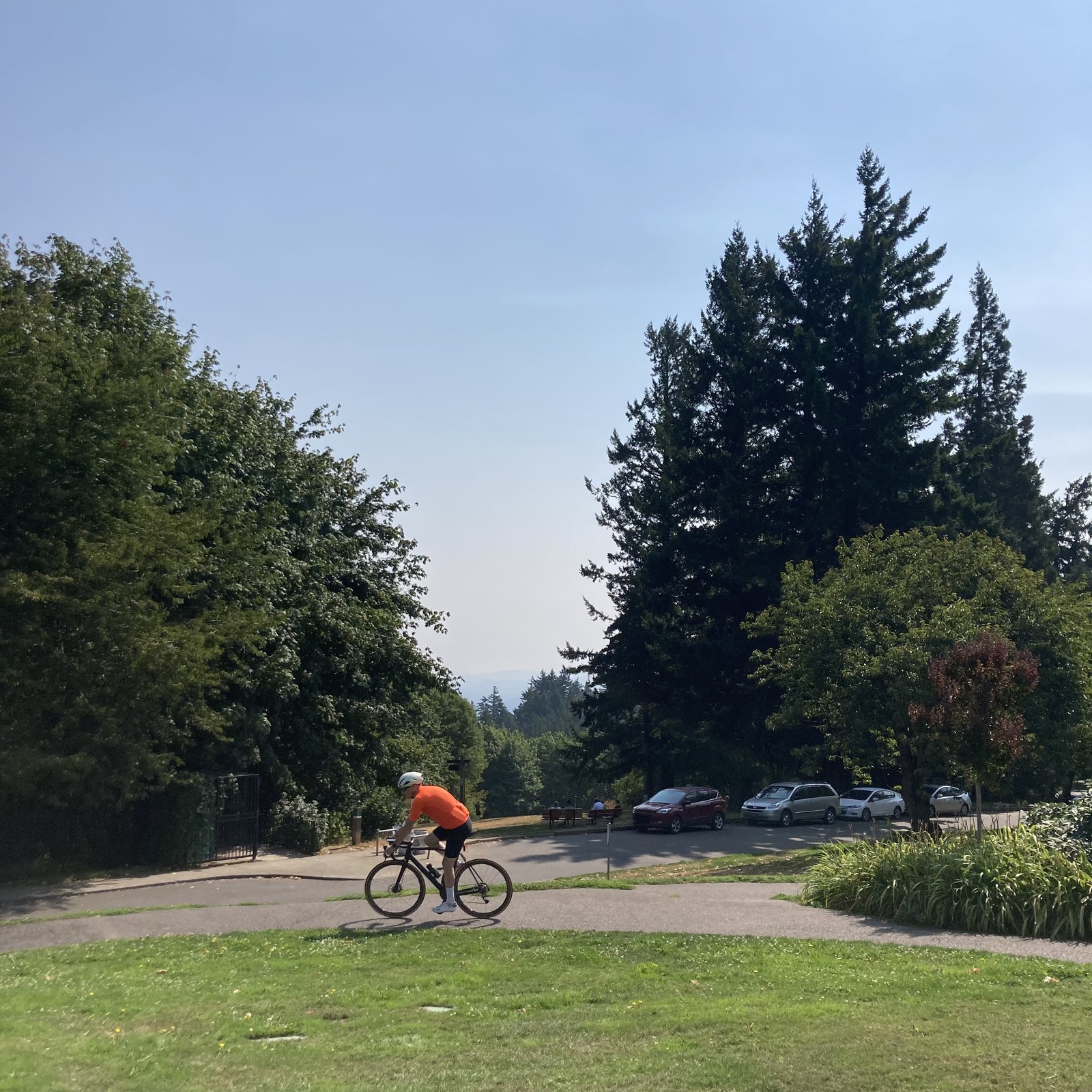 Mt Hood should be visible on this cloudless day but is not due to humidity and wildfire haze. In the foreground a cyclist rides past on the sidewalk
