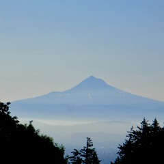 Silhouette of a lone volcanic peak a few hours after sunrise. A low haze throws the intervening foothills into crisp relief