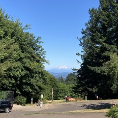Mt. Hood, still rather snowy for mid-July, on a brilliantly clear day, seen from Council Crest Park. About 100' away, four people in hats are admiring the mountain