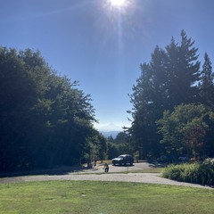 View of Mt. Hood from Council Crest on a crystal clear August morning. about 50' away a cyclist is climbing up the short hill from the road to the top of the hill, toward us